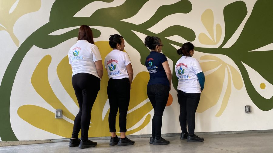 Four members of the California Refresh team in their logo shirts in front of a mural